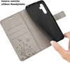 A hand is holding a black phone case, demonstrating its insertion into a gray flip case with card slots and a floral design. Produktbild-Vorschau