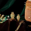 Two gold digital watches are displayed on a brown cloth, with a chessboard and chess pieces in the background, and a wooden jewelry box with a necklace in the upper right corner. Voir les images du produit