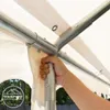 A hand is shown holding a metal pole of a white party tent structure. Voir les images du produit