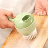 A hand is holding a green and white electric vegetable cutter with a brush attachment, cleaning a wooden cutting board with soap and water. Náhled obrázku produktu