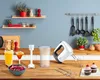 A kitchen counter scene with a hand mixer, blender attachment, drinks, and cupcakes. Produktbild-Vorschau