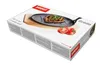 The image shows the retail packaging for a cast iron grill pan with a wooden board. The packaging features a picture of the product with a steak and tomatoes, along with branding and product information. Voir les images du produit