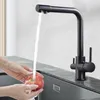 A person is washing an apple under a black faucet in a modern kitchen sink. Produktbild-Vorschau