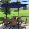 A patio set with a navy blue umbrella, table, and chairs, set up on a paved patio with a grassy backyard visible. Produktbild-Vorschau