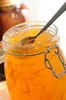 A close-up shot of a jar of orange jam with a spoon in it. Anteprima dell’immagine prodotto