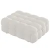 A beige upholstered ottoman with a tufted, bubble-like design, shown from a side angle on a white background. Produktbild-Vorschau