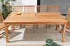 A wooden dining table and chairs set on a wooden deck, with plants in the background. Produktbild-Vorschau