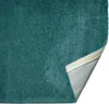 A close-up, angled view of a teal rug, with one corner folded back to show the underside. Produktbild-Vorschau