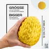 A hand is holding a yellow, textured egg-shaped object. Text overlays highlight its size compared to competitors. Voir les images du produit