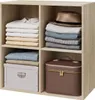 A light brown wooden shelving unit filled with neatly folded clothes, a hat, a storage box, and a makeup case. Náhľad obrázku produktu