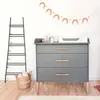 A nursery room with a changing table, a ladder shelf, and a basket. Produktbild-Vorschau