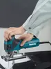 A person is using a teal and black jigsaw to cut a black material. Produktbild-Vorschau