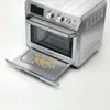 A silver air fryer oven with its crumb tray pulled out, showing some crumbs on it. Podgląd zdjęcia produktu