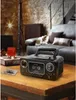 A retro-style stereo system with a cassette player is placed on a wooden table in a living room setting. Voir les images du produit