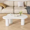 A white, cloud-shaped coffee table in front of a light beige sofa. Produktbild-Vorschau