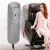 A woman in pink pajamas sits in a recliner chair, while a remote control for the chair is in the foreground. Produktbild-Vorschau