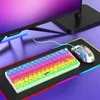 A gaming keyboard and mouse are displayed on a colorful RGB mousepad, with a monitor in the background. Produktbild-Vorschau