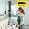 A woman is cleaning a mirror with a steam cleaner in a modern bathroom. Produktbild-Vorschau
