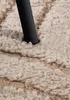 A close-up view of a textured rug with a dark leg of furniture pressing into it. Anteprima dell’immagine prodotto
