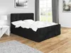 A black boxspring bed with white bedding is shown in a bedroom setting with wooden floors, a grey rug, and a window with curtains in the background. Produktbild-Vorschau