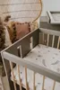 A nursery room scene with a crib, a peacock chair, and a pillow. Náhled obrázku produktu