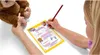 A child is filling out a certificate with a toy monkey next to them. Podgląd zdjęcia produktu