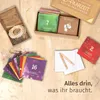 A collection of advent calendar cards and related items laid out on a wooden surface. Produktbild-Vorschau