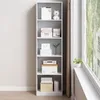 A white bookshelf filled with various items, placed next to a window with a view of trees and buildings. Produktbild-Vorschau