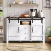 A white and black sideboard with sliding doors and drawers, styled in a rustic farmhouse aesthetic, is shown in a room setting with a shelf above and a rug on the floor. Voir les images du produit