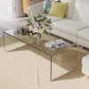 A glass coffee table in a living room setting with a sofa and a rug. Voir les images du produit