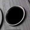 A close-up view of a black speaker with a textured gray background. Produktbild-Vorschau