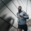 A man is running in front of a modern building with metallic walls. Podgląd zdjęcia produktu