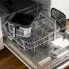The interior of a dishwasher with a hot air fryer basket and accessories inside. Náhľad obrázku produktu