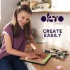 A young girl is shown creating a 3D art piece on a wooden table, with the OKTO logo and marketing text visible. Produktbild-Vorschau