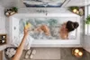 A woman relaxing in a bubble bath with a drink. Produktbild-Vorschau