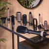 A collection of hair styling attachments and a hair dryer are displayed on a glass shelf in front of a wood-paneled wall. Anteprima dell’immagine prodotto