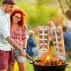 A couple is grilling salmon on wooden boards over an open fire in an outdoor setting. Produktbild-Vorschau