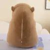 The back of a brown plush capybara toy is shown, sitting on a patterned surface. Podgląd zdjęcia produktu