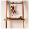 A wooden monkey toy hanging from a wooden rack, with a small wooden bird on a shelf below. Náhled obrázku produktu