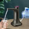 A person is holding a glass while an electric water dispenser pumps water into it from a large water bottle. Produktbild-Vorschau