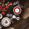 A beautifully set dining table with Christmas-themed plates, cutlery, glasses, and a bouquet of red amaryllis flowers. Anteprima dell’immagine prodotto