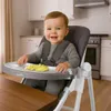 A baby sitting in a high chair in a kitchen. Voir les images du produit