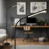 Two LED floor lamps are shown in a modern home office setting. One lamp is in the foreground, with its flexible neck bent, and the other is in the background, standing tall. Anteprima dell’immagine prodotto