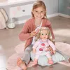 A young girl is playing with a doll, brushing its hair. Produktbild-Vorschau