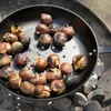 Chestnuts being roasted in a pan over coals. Produktbild-Vorschau
