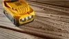 A yellow DeWalt battery pack sits on a wooden surface covered in sawdust. Anteprima dell’immagine prodotto
