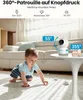 A baby crawling on the floor with a security camera on a table in the background. Produktbild-Vorschau