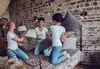 Three young women are having a pillow fight on a bed in a rustic room. Podgląd zdjęcia produktu