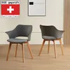 Two modern dining chairs with gray seats and light-colored wooden legs are placed in a room with a light wall and wooden floor. A framed piece of art hangs on the wall behind the chairs. Produktbild-Vorschau