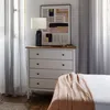 A bedroom scene featuring a white dresser with a wooden top, a lamp, and artwork. Anteprima dell’immagine prodotto